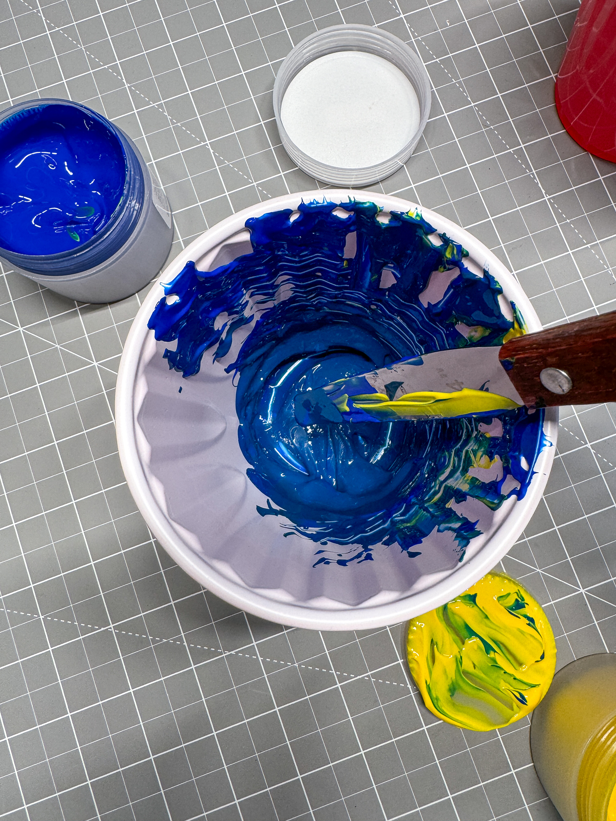mixing blue and yellow screen printing ink in a cup
