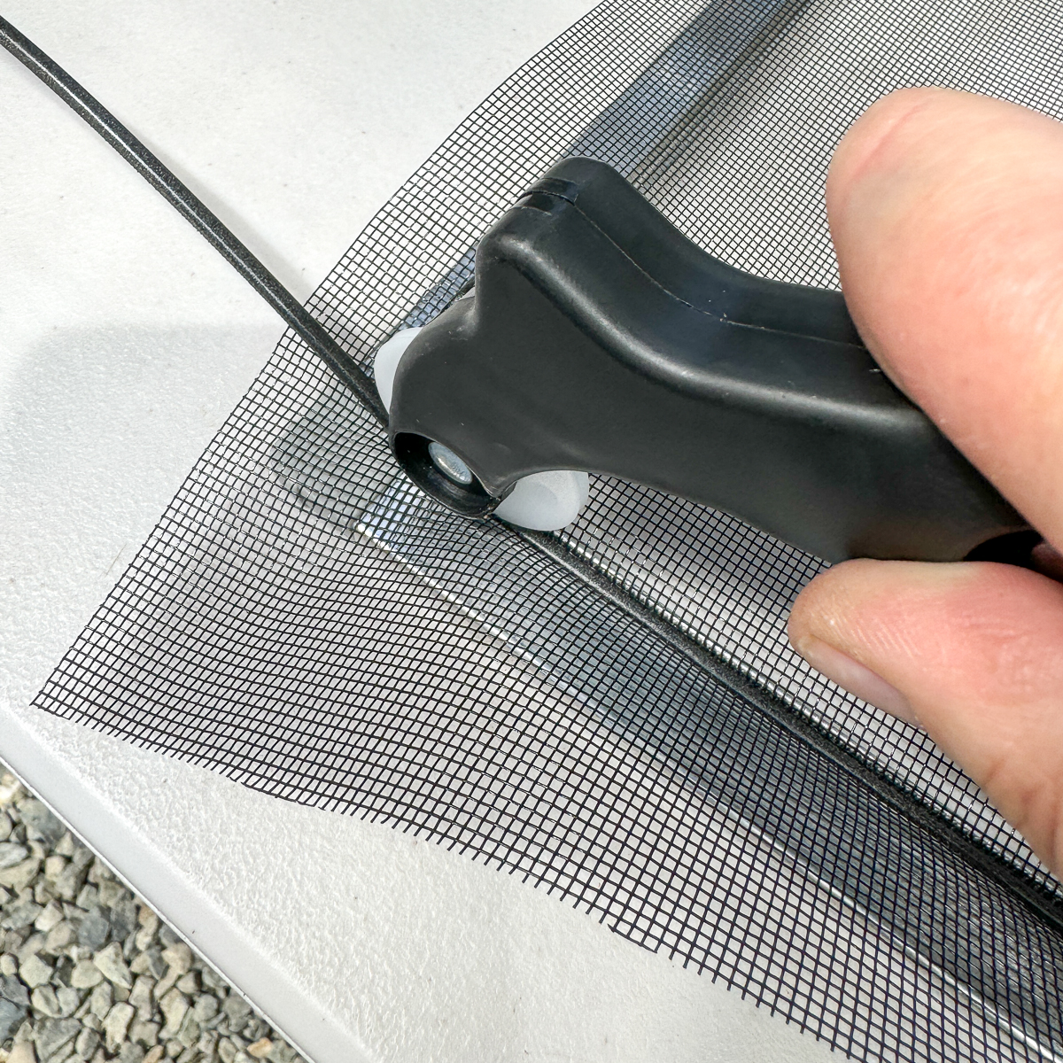 using the spline roller to press the rubber spline into the groove of the window screen frame