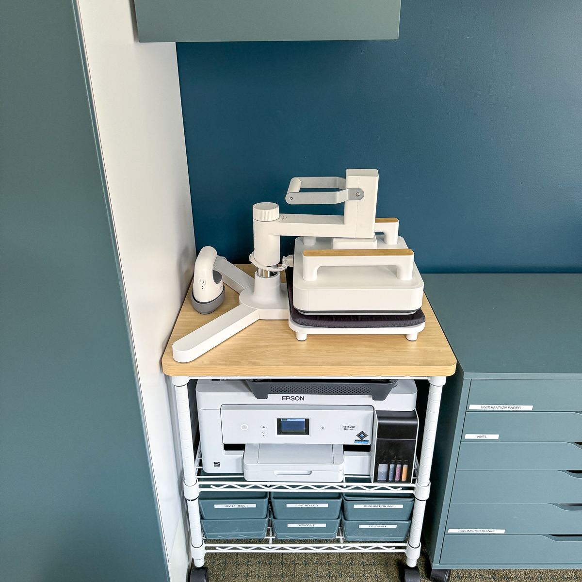 xTool all-in-one heat press system on printer cart under a wall cabinet