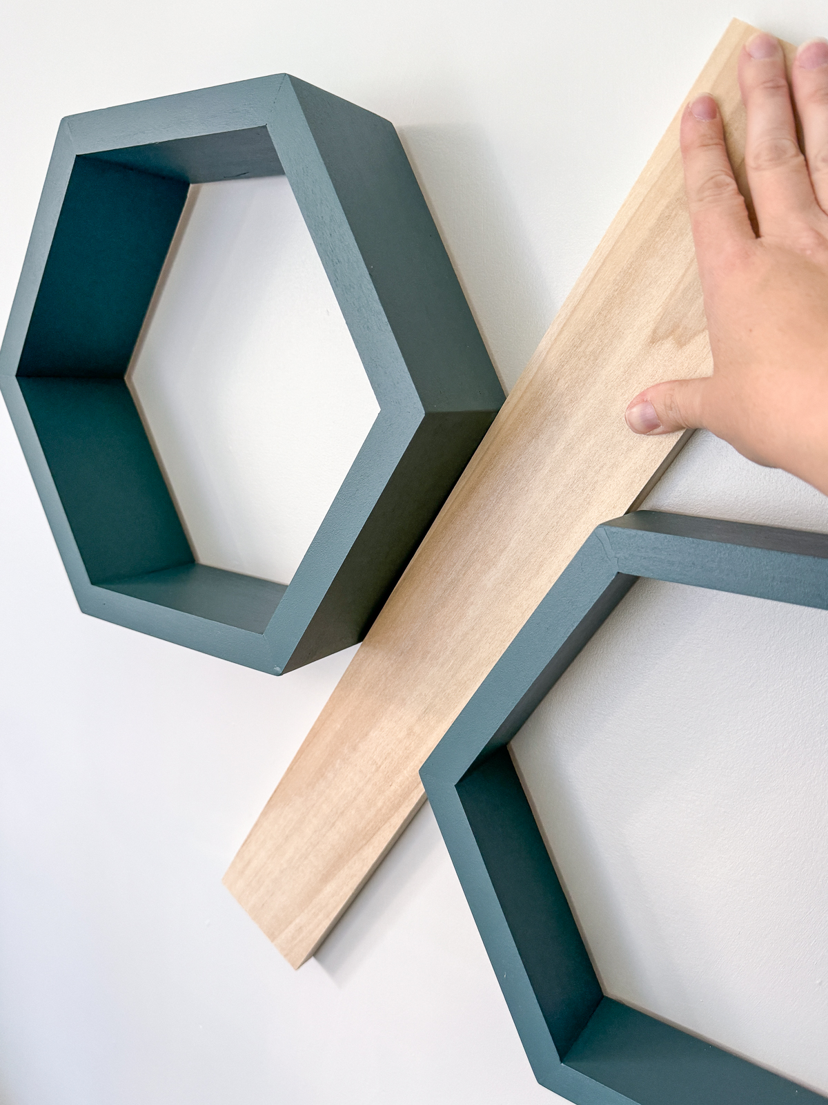 using a scrap of wood as a spacer between the hexagon shelves