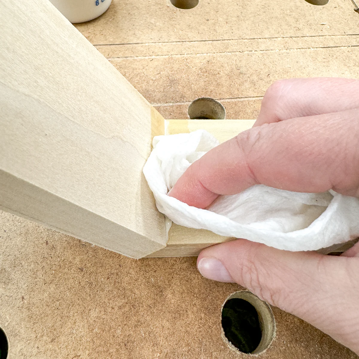 wiping off excess wood glue from corner of hexagon shelf