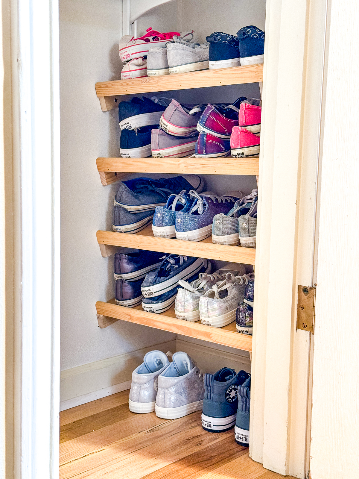 DIY slanted shoe shelves in closet full of Converse sneakers