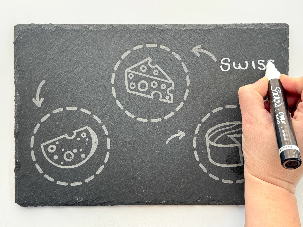 writing the cheese variety on the engraved slate tray with a chalk marker