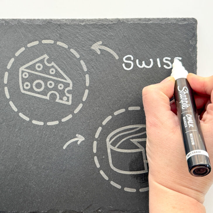 writing with chalk on an engraved slate cheese board