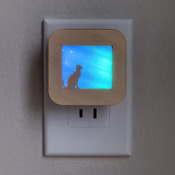 DIY night light cover with the silhouette of a cat looking at the northern lights in the sky