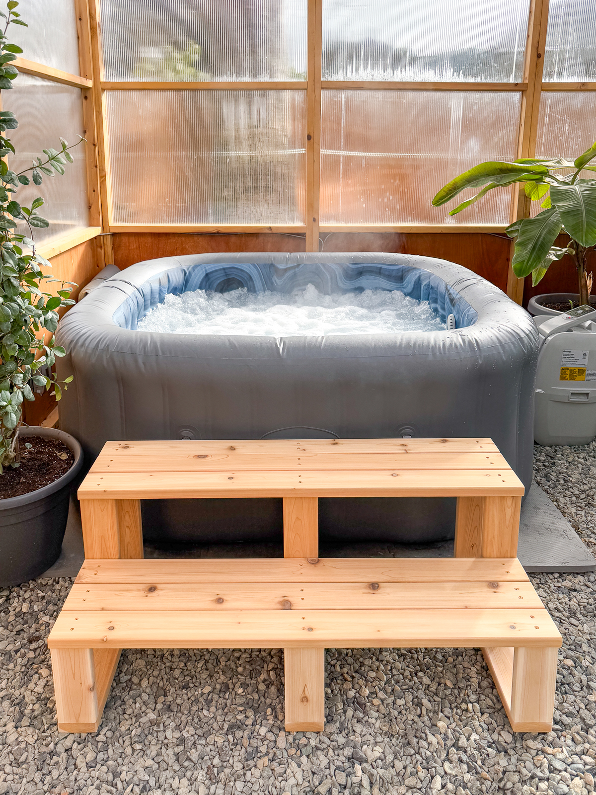 DIY hot tub steps in front of inflatable hot tub in greenhouse