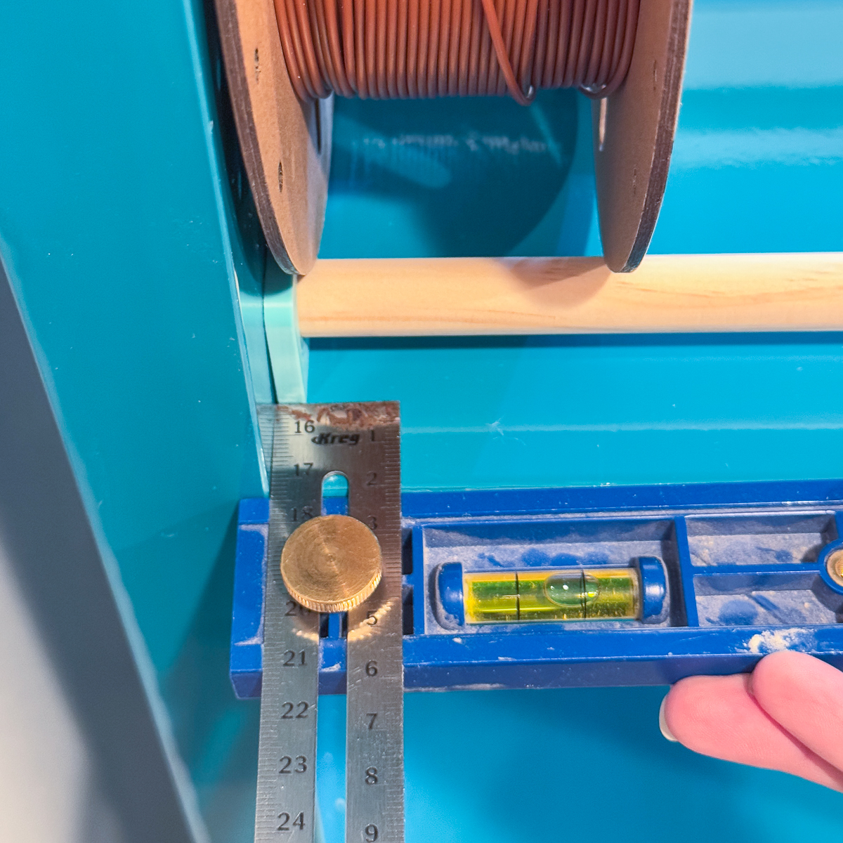 using the Kreg multi-mark tool to measure the distance from the front of the shelf to the bracket